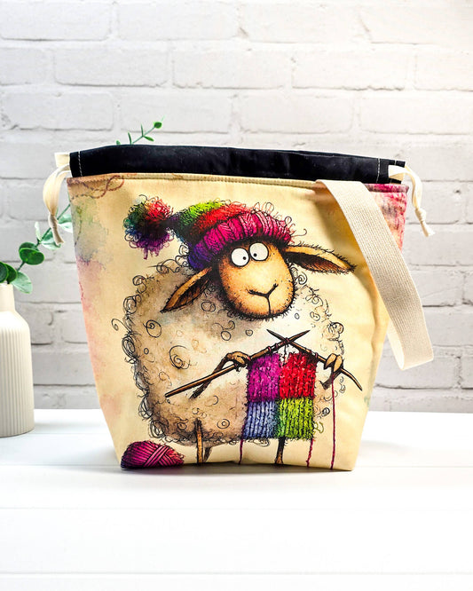 Stricktasche mit strickendem Schaf, bunter Mütze, Stricknadeln und Wollknäuel auf hellem Grund, handgenäht in Bayern von NadelMikado.
