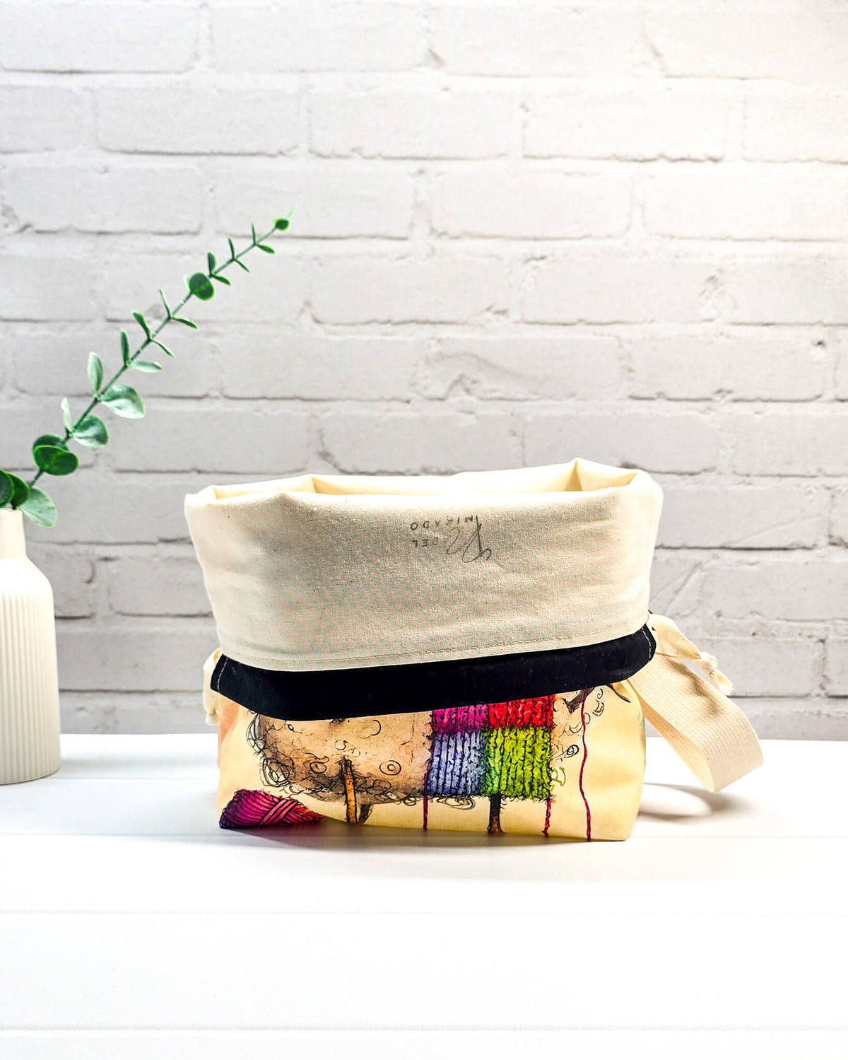 Stricktasche mit strickendem Schaf, bunter Mütze, Stricknadeln und Wollknäuel auf hellem Grund, handgenäht in Bayern von NadelMikado.