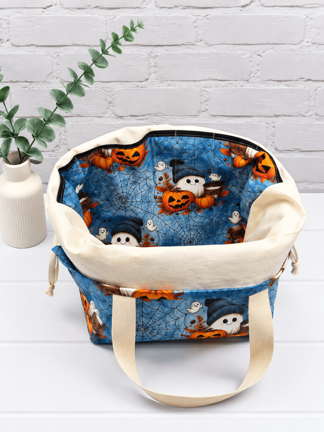 Große Stricktasche mit Geistern, Kürbissen, Kaffeebechern und Spinnennetzen auf blauem Stoff. Handgenäht in Bayern von NadelMikado.