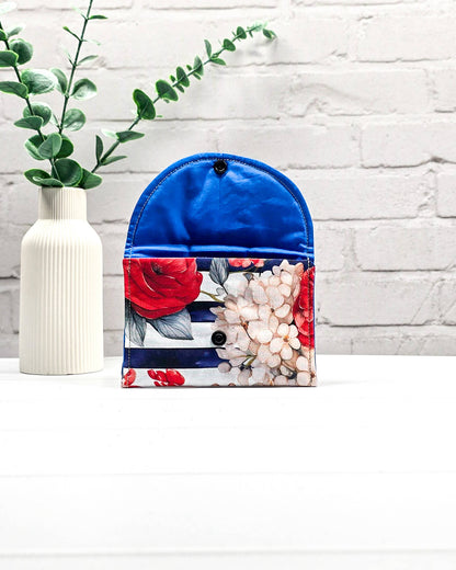 Mini Pouch mit roten und cremefarbenen Blüten auf dunkelblau-weiß gestreiftem Stoff, leuchtend blauer Innenklappe und schwarzen Druckknöpfen. Kleine Zubehörtasche für Maschenmarkierer und Strickzubehör. Handgenäht in Bayern von NadelMikado.