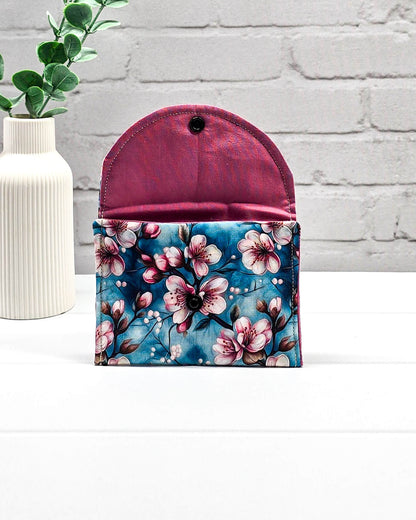 Kleine Mini Pouch mit rosa Kirschblütenmotiv auf blauem Grund und einem schwarzen Druckknopf. Handgenäht in Bayern von Nadelmikado.