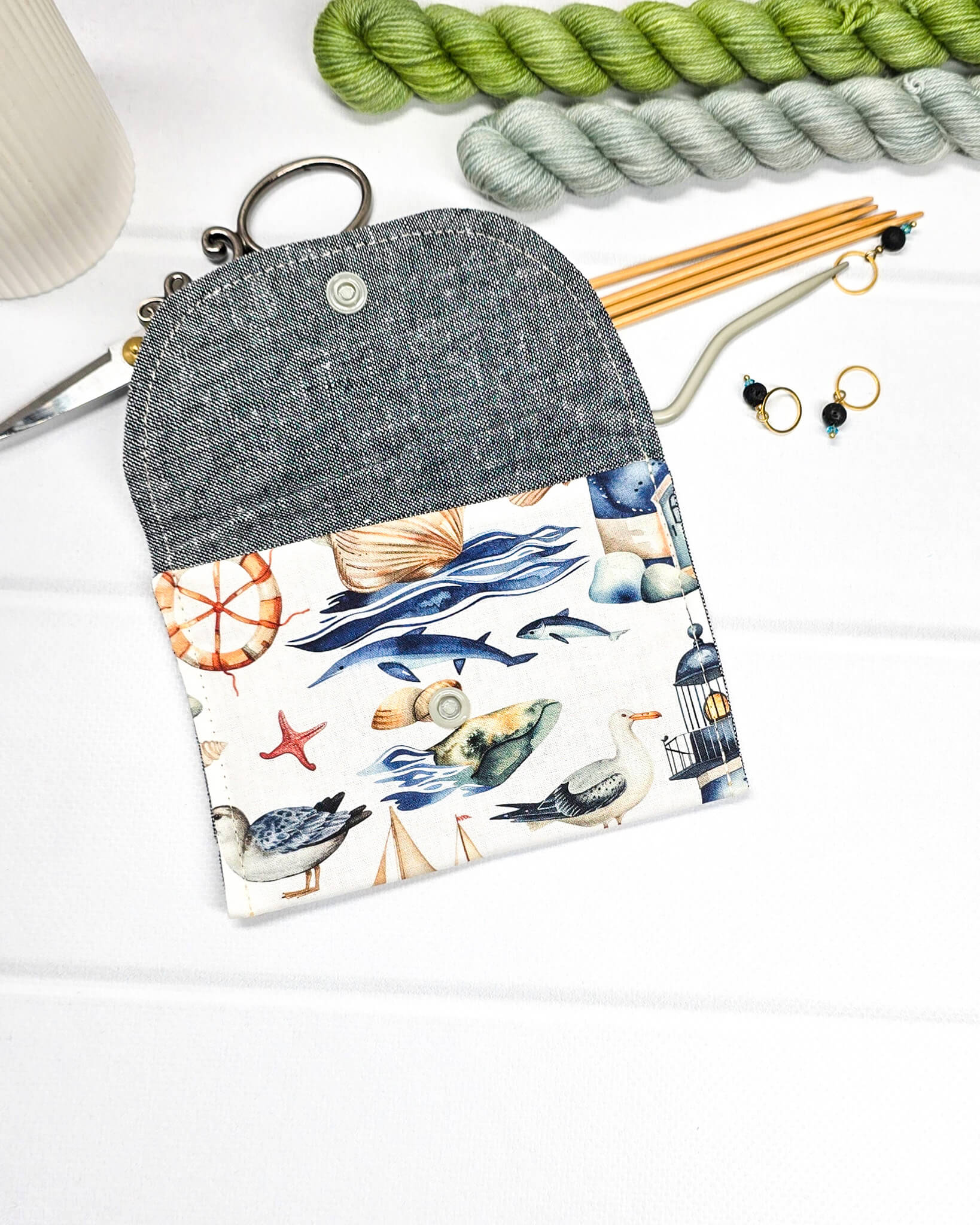Mini Pouch mit einem maritimen Muster aus Möwen, Segelbooten und Leuchttürmen, geschwungener Klappe und einem hellen Druckknopf. Handgenäht in Bayern von Nadelmikado