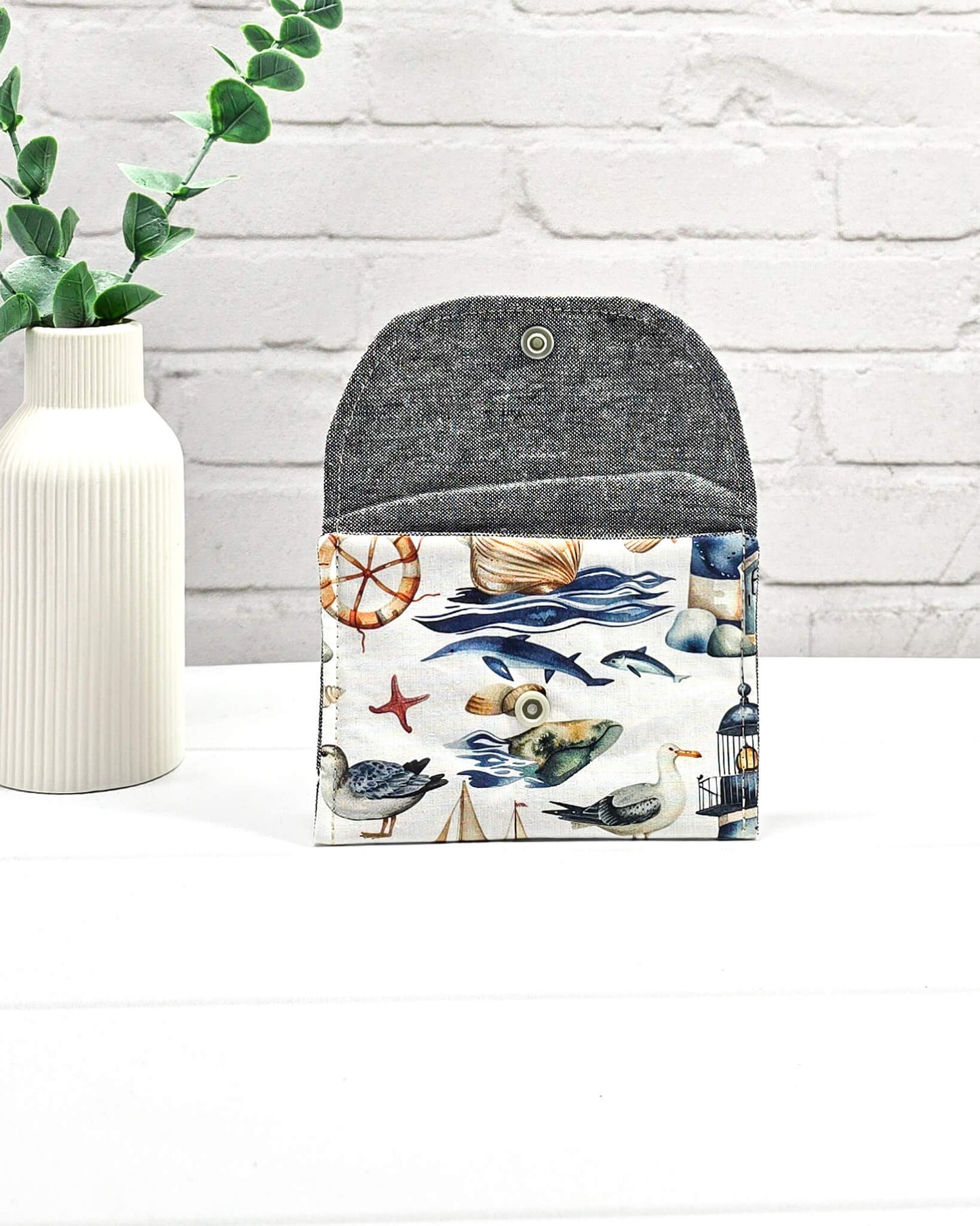 Mini Pouch mit einem maritimen Muster aus Möwen, Segelbooten und Leuchttürmen, geschwungener Klappe und einem hellen Druckknopf. Handgenäht in Bayern von Nadelmikado