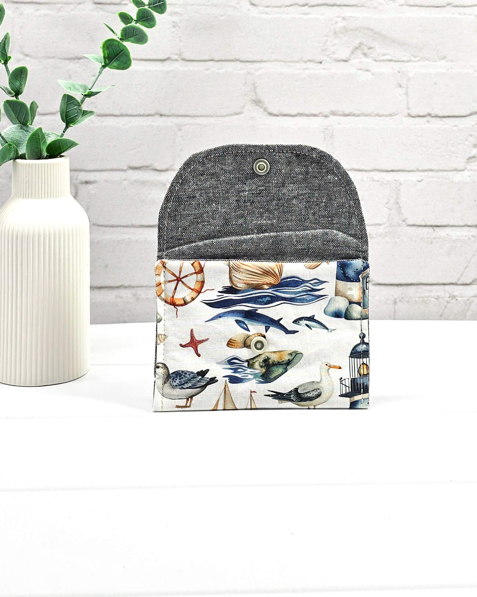 Mini Pouch mit einem maritimen Muster aus Möwen, Segelbooten und Leuchttürmen, geschwungener Klappe und einem hellen Druckknopf. Handgenäht in Bayern von Nadelmikado