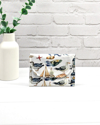 Mini Pouch mit einem maritimen Muster aus Möwen, Segelbooten und Leuchttürmen, geschwungener Klappe und einem hellen Druckknopf. Handgenäht in Bayern von Nadelmikado