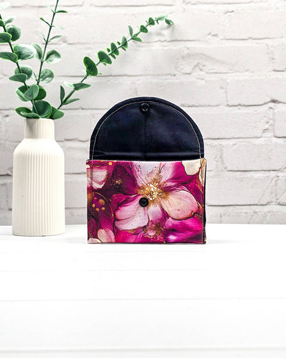 Geöffnete Mini Pouch mit großen pink-rosafarbenen Blüten und goldenen Akzenten, schwarzer Innenklappe und Druckknopfverschluss. Kleine Zubehörtasche für Maschenmarkierer und Strickzubehör. Handgenäht in Bayern von NadelMikado.