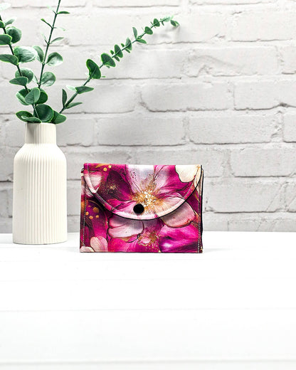 Geöffnete Mini Pouch mit großen pink-rosafarbenen Blüten und goldenen Akzenten, schwarzer Innenklappe und Druckknopfverschluss. Kleine Zubehörtasche für Maschenmarkierer und Strickzubehör. Handgenäht in Bayern von NadelMikado.