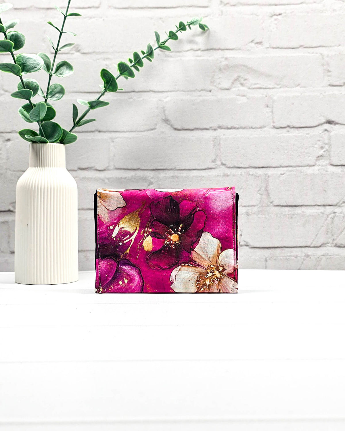 Geöffnete Mini Pouch mit großen pink-rosafarbenen Blüten und goldenen Akzenten, schwarzer Innenklappe und Druckknopfverschluss. Kleine Zubehörtasche für Maschenmarkierer und Strickzubehör. Handgenäht in Bayern von NadelMikado.