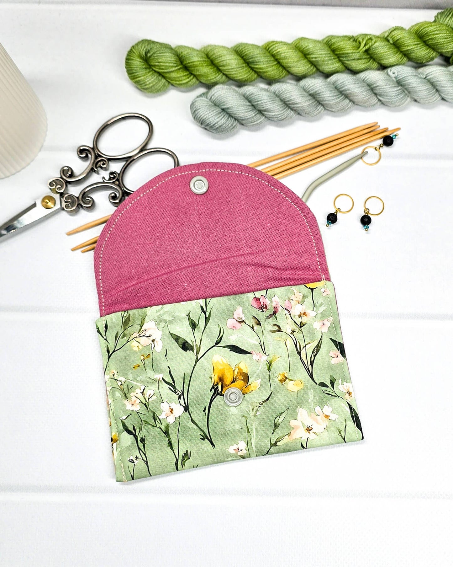Kleine Mini Pouch mit buntem Wildblumenmotiv auf salbeigrünem Grund und einem hellgrauen Druckknopf. Handgenäht in Bayern von Nadelmikado.