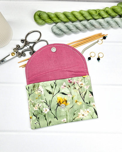 Kleine Mini Pouch mit buntem Wildblumenmotiv auf salbeigrünem Grund und einem hellgrauen Druckknopf. Handgenäht in Bayern von Nadelmikado.