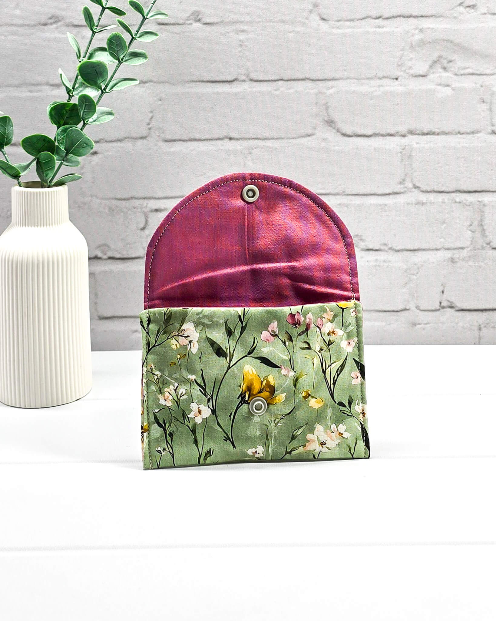 Kleine Mini Pouch mit buntem Wildblumenmotiv auf salbeigrünem Grund und einem hellgrauen Druckknopf. Handgenäht in Bayern von Nadelmikado.