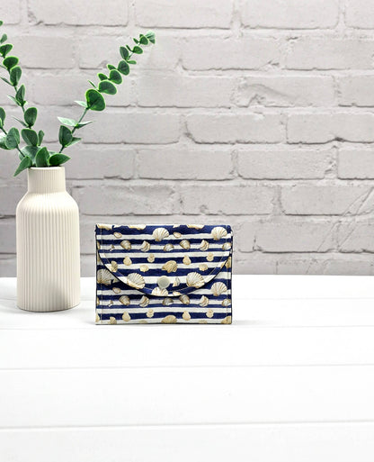 Kleine Mini Pouch aus blau-weiß quergestreiftem Stoff mit kleinen Muschelmotiven und einem hellgrauen Druckknopf auf der geschwungenen Klappe. Handgenäht in Bayern von Nadelmikado. 