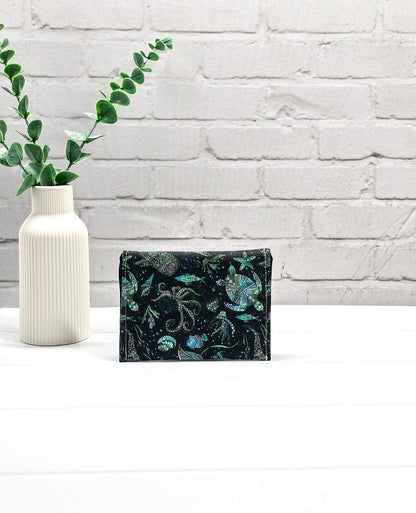 Kleine Mini Pouch aus schwarzem Stoff mit leuchtend grünen und türkisen Tiefsee-Motiven und einem schwarzen Druckknopf auf der Verschlussklappe. Handgenäht in Bayern von Nadelmikado. 