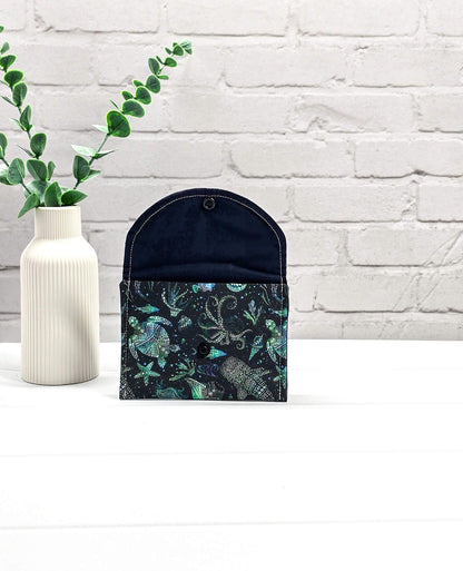 Kleine Mini Pouch aus schwarzem Stoff mit leuchtend grünen und türkisen Tiefsee-Motiven und einem schwarzen Druckknopf auf der Verschlussklappe. Handgenäht in Bayern von Nadelmikado. 