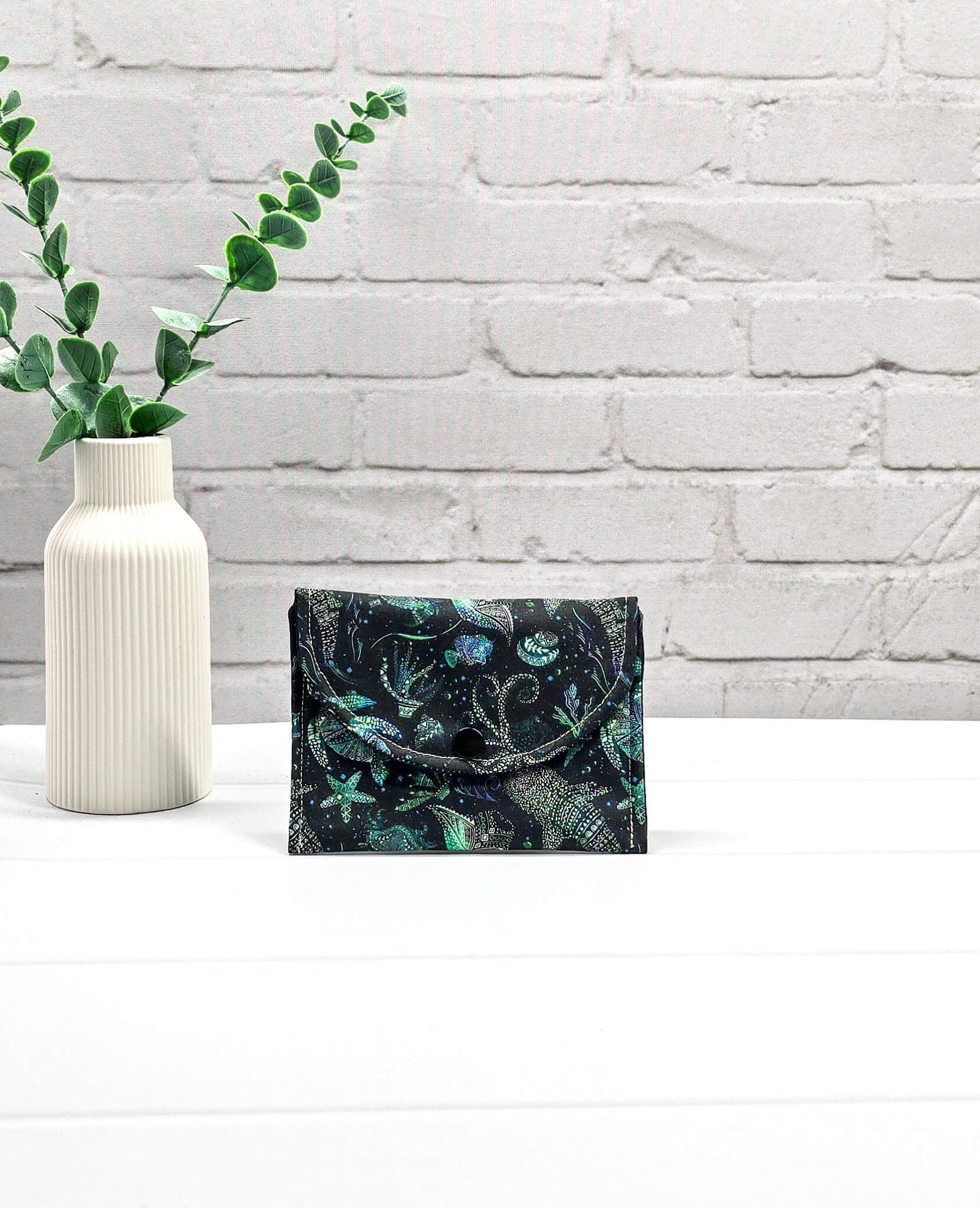 Kleine Mini Pouch aus schwarzem Stoff mit leuchtend grünen und türkisen Tiefsee-Motiven und einem schwarzen Druckknopf auf der Verschlussklappe. Handgenäht in Bayern von Nadelmikado. 