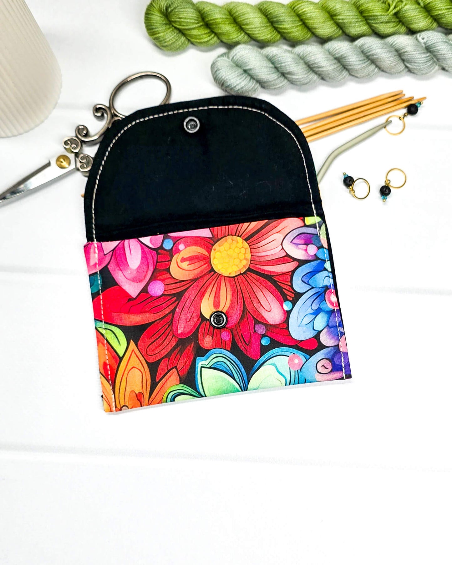 Kleine, flache Mini-Pouch für Handarbeitszubehör mit einem farbenfrohen, großflächigen Blumenmuster, verschlossen mit einer Klappe und einem schwarzen Druckknopf. Handgenäht in Bayern von Nadelmikado