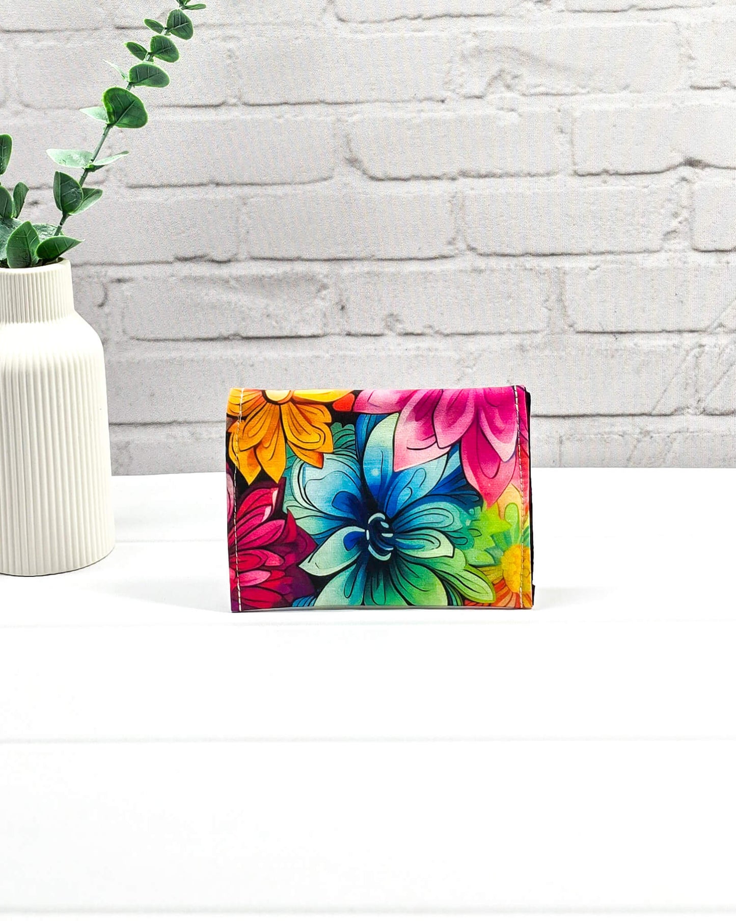 Kleine, flache Mini-Pouch für Handarbeitszubehör mit einem farbenfrohen, großflächigen Blumenmuster, verschlossen mit einer Klappe und einem schwarzen Druckknopf. Handgenäht in Bayern von Nadelmikado