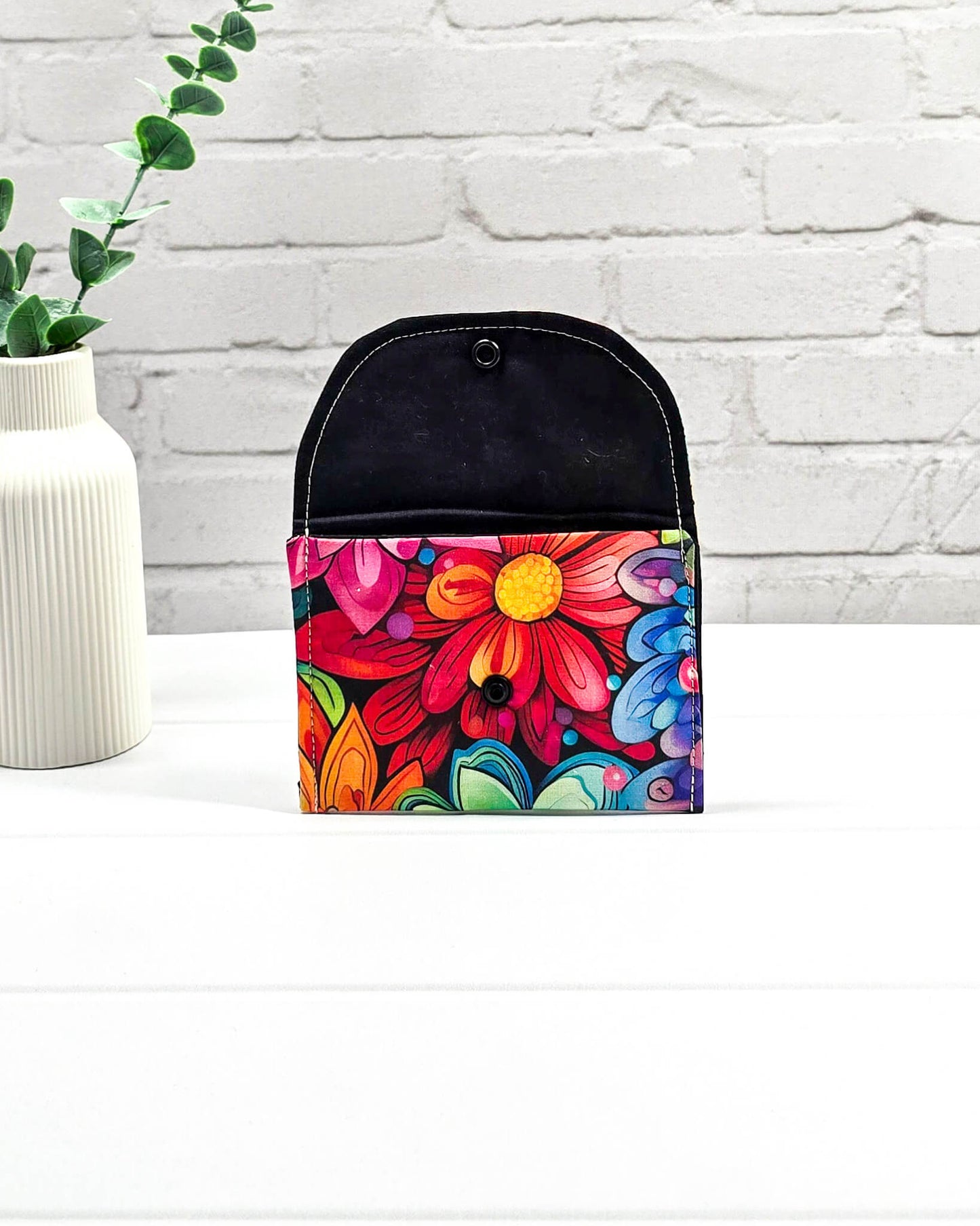 Kleine, flache Mini-Pouch für Handarbeitszubehör mit einem farbenfrohen, großflächigen Blumenmuster, verschlossen mit einer Klappe und einem schwarzen Druckknopf. Handgenäht in Bayern von Nadelmikado