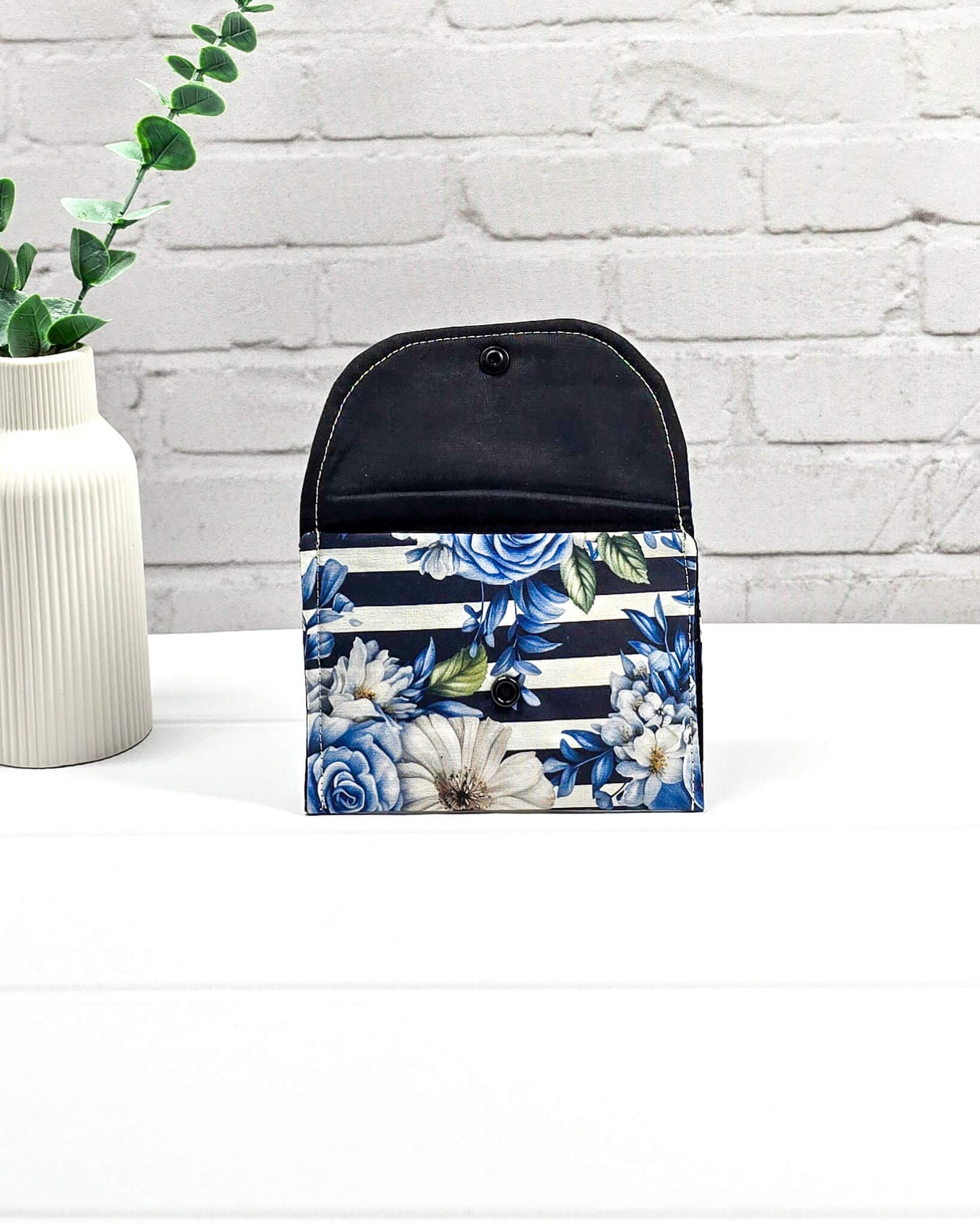 Kleine, flache Mini-Pouch für Handarbeitszubehör mit blauen Rosen und weißen Blüten auf blau-weiß gestreiftem Stoff, verschlossen mit einer Klappe und einem schwarzen Druckknopf. Handgenäht in Bayern von Nadelmikado