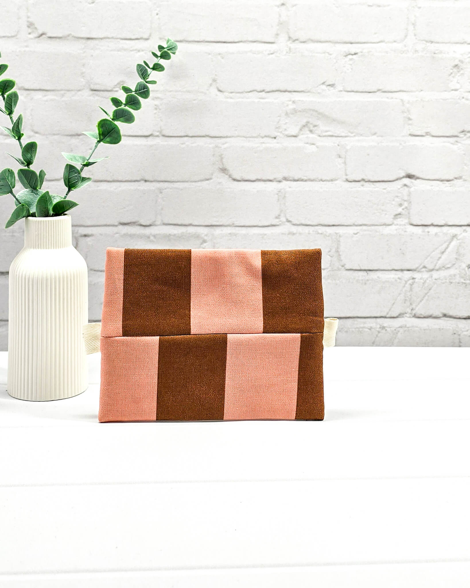 Mini Zip Pouch mit breiten vertikalen Streifen in Braun und Rosa, einem schwarzen, mittigen Reißverschluss und hellen Stofflaschen. Handgenäht in Bayern von Nadelmikado. 