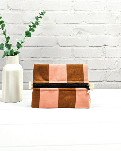 Mini Zip Pouch mit breiten vertikalen Streifen in Braun und Rosa, einem schwarzen, mittigen Reißverschluss und hellen Stofflaschen. Handgenäht in Bayern von Nadelmikado. 