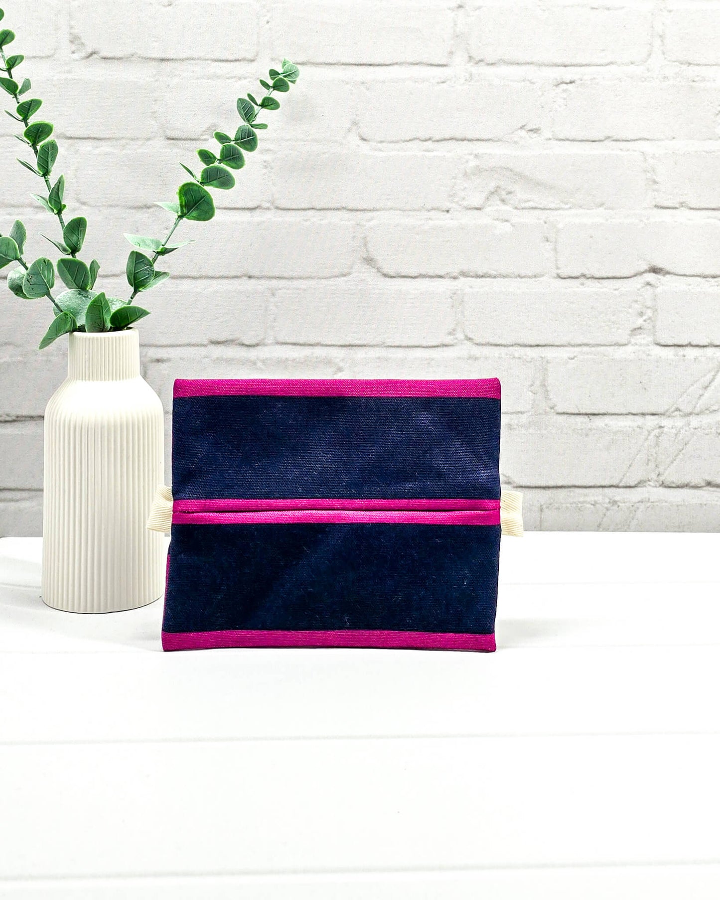 Mini Zip Pouch mit breiten horizontalen Streifen in Fuchsia und Dunkelblau, einem schwarzen mittigen Reißverschluss und hellen Stofflaschen. Handgenäht in Bayern von Nadelmikado. 