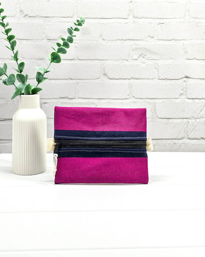 Mini Zip Pouch mit breiten horizontalen Streifen in Fuchsia und Dunkelblau, einem schwarzen mittigen Reißverschluss und hellen Stofflaschen. Handgenäht in Bayern von Nadelmikado. 