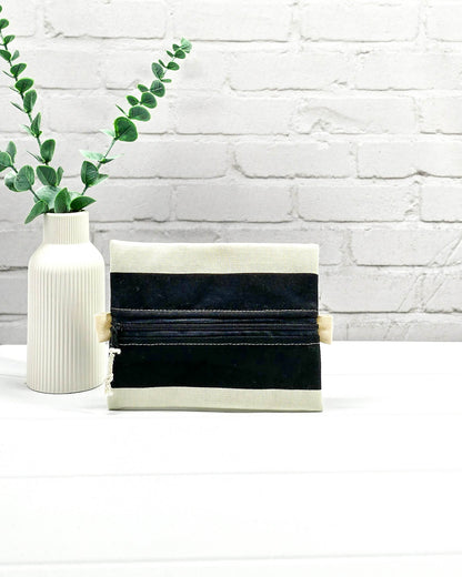 Mini Zip Pouch mit breiten horizontalen Streifen in Schwarz und Creme, einem schwarzen mittigen Reißverschluss und hellen Stofflaschen. Handgenäht in Bayern von Nadelmikado. 