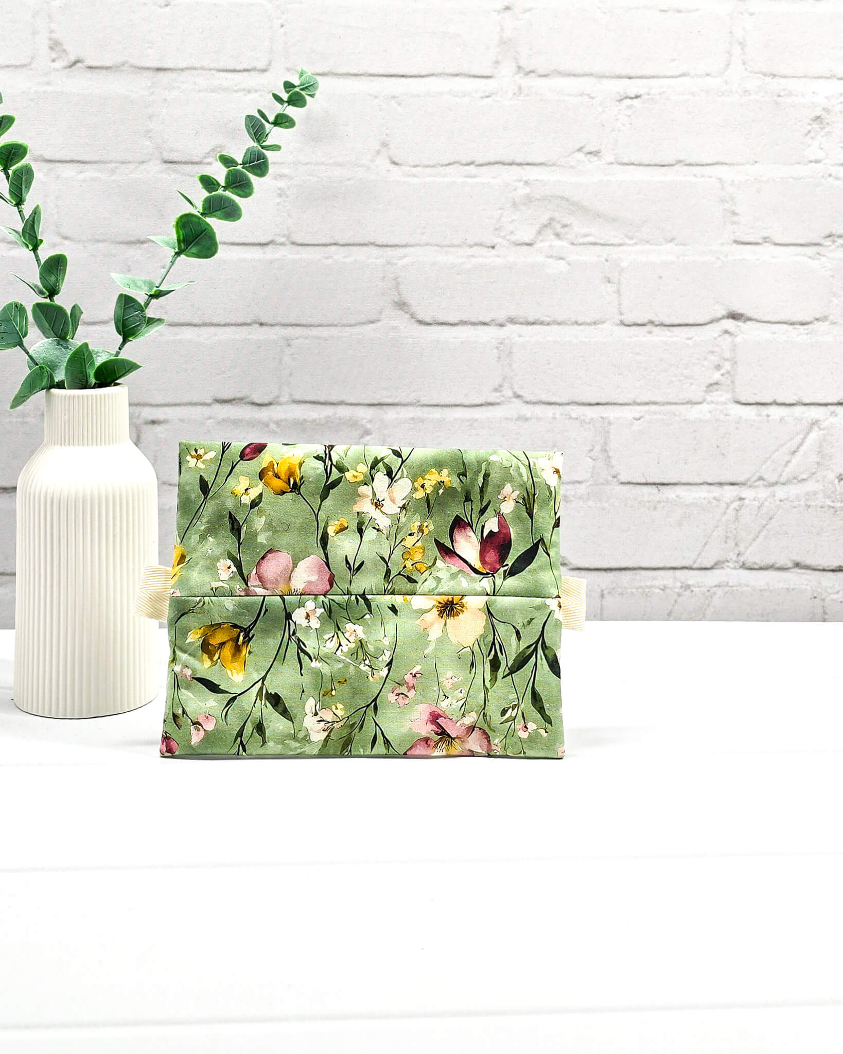 Mini Zip Pouch mit einem floralen Muster auf olivgrünem Stoff, einem rosafarbenen mittigen Reißverschluss und hellen Stofflaschen. Handgenäht in Bayern von Nadelmikado. 