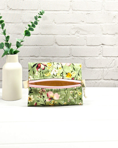 Mini Zip Pouch mit einem floralen Muster auf olivgrünem Stoff, einem rosafarbenen mittigen Reißverschluss und hellen Stofflaschen. Handgenäht in Bayern von Nadelmikado. 