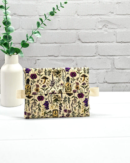 Kleine Reißverschlusstasche Mini Zip Pouch mit lila Reißverschluss, seitlichen hellen Laschen und botanischem Kräuterküche-Muster auf beigem Grund. Handgenäht in Bayern von Nadelmikado.