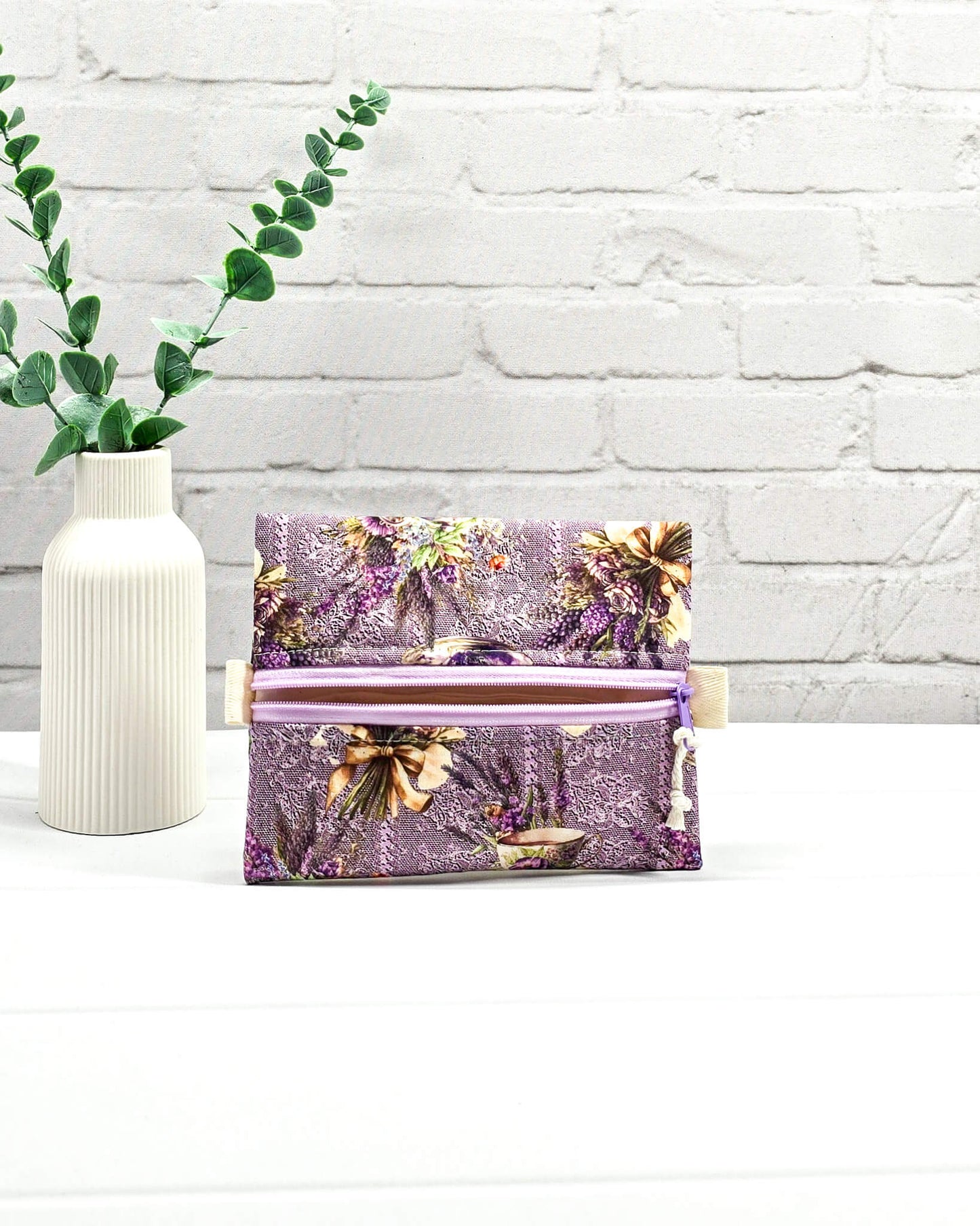 Mini Zip Pouch mit einem lila Lavendel- und Teetassen-Muster, einem hellvioletten mittigen Reißverschluss und hellen Stofflaschen. Handgenäht in Bayern von Nadelmikado. 