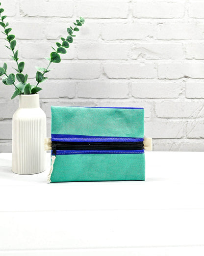 Mini Zip Pouch in Mintgrün mit einem blauen Kontraststreifen, einem schwarzen mittigen Reißverschluss und hellen Stofflaschen. Handgenäht in Bayern von Nadelmikado. 