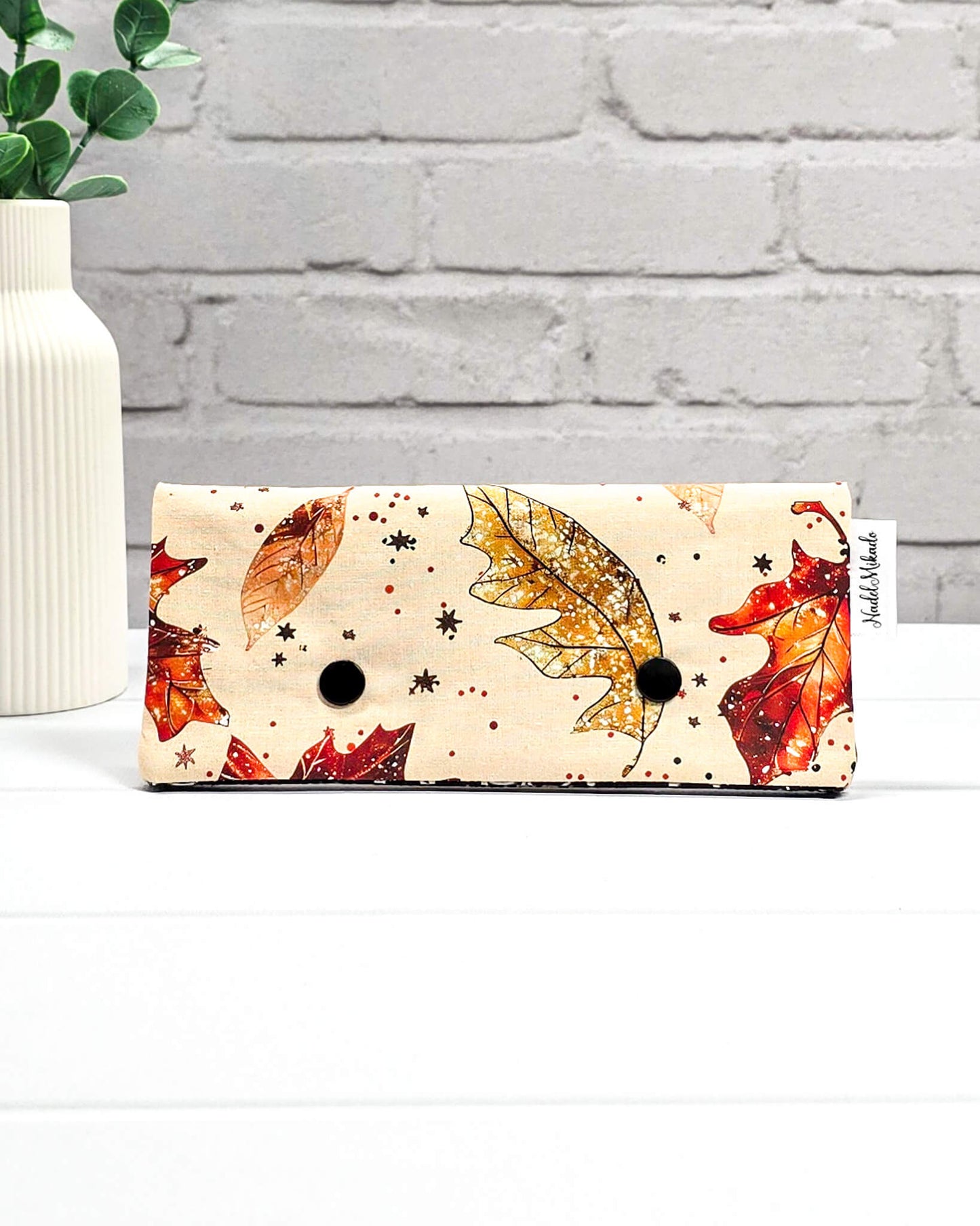 Nadelgarage für 15 cm lange Nadelspiele mit zwei schwarzen Druckknöpfen und herbstlichem Ahornblatt-Muster auf beigefarbenem Grund. Handgenäht in Bayern von Nadelmikado.
