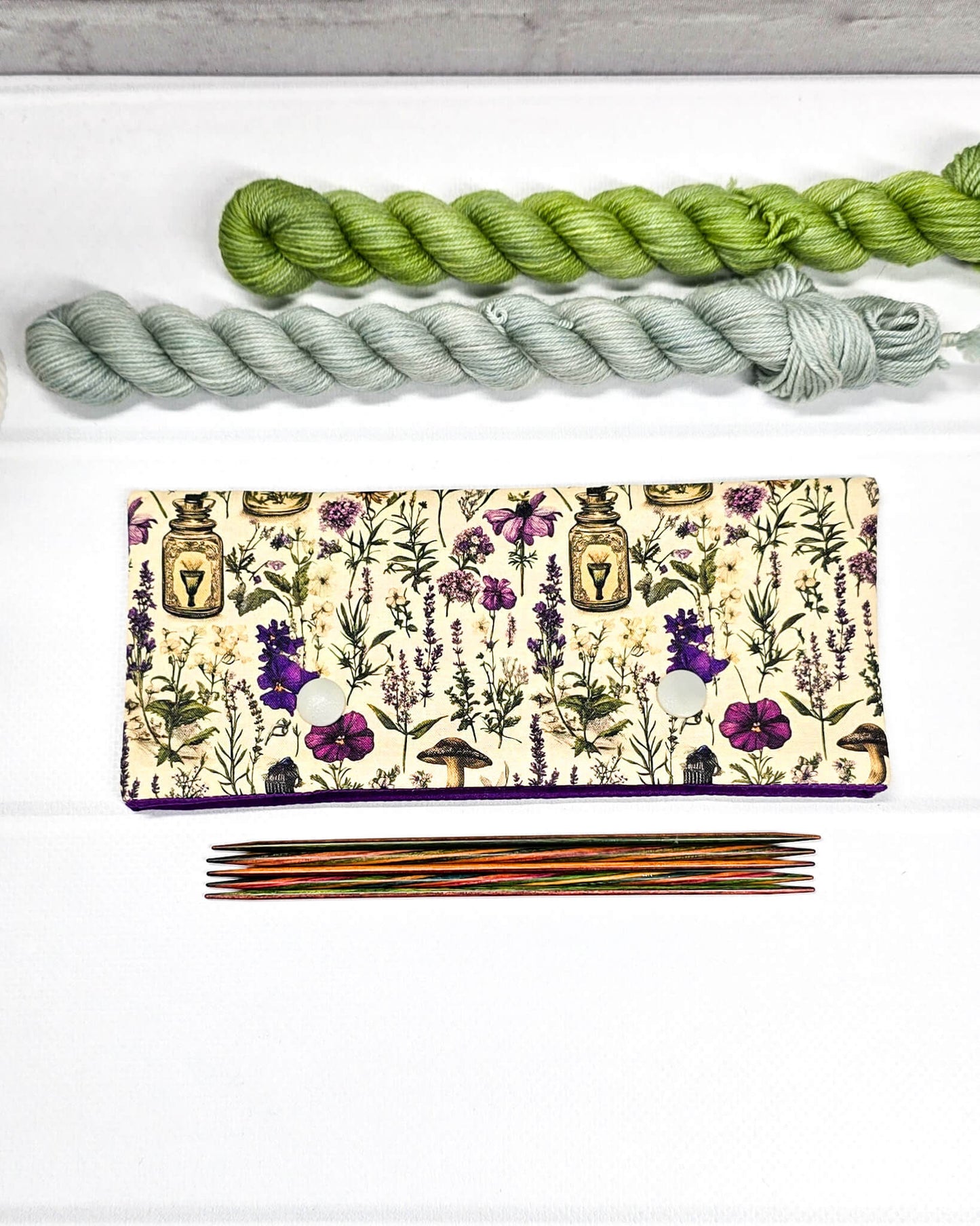 Nadelgarage für 15 cm lange Nadelspiele mit zwei hellen Druckknöpfen und botanischem Kräuterküche-Muster auf beigem Grund. Handgenäht in Bayern von Nadelmikado.