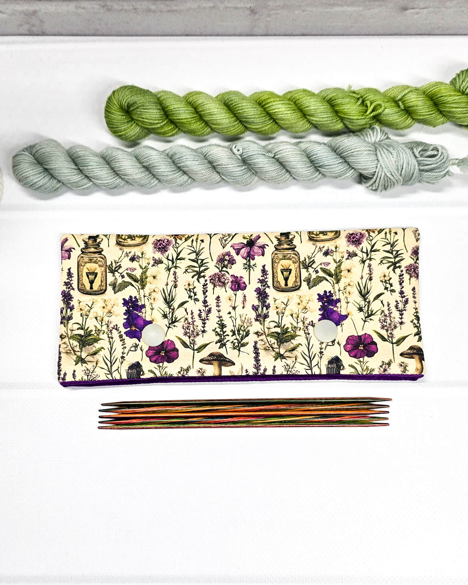 Nadelgarage für 15 cm lange Nadelspiele mit zwei hellen Druckknöpfen und botanischem Kräuterküche-Muster auf beigem Grund. Handgenäht in Bayern von Nadelmikado.