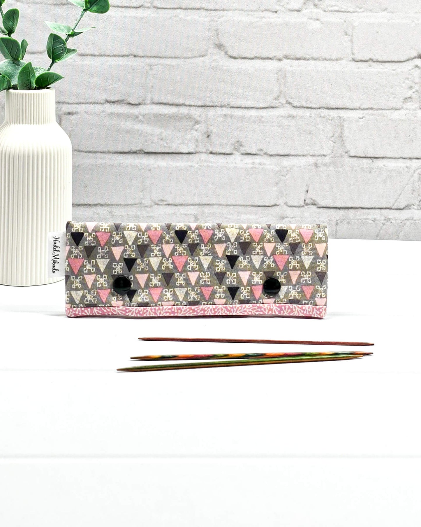 Nadelgarage für 15 cm lange Nadelspiele sichert das Sockenstrickzeug und verhindert fallengelassene Maschen. Grafisches Retromuster mit kleinen Dreiecken in Rosa, Grau und Schwarz. Handgenäht in Bayern von Nadelmikado