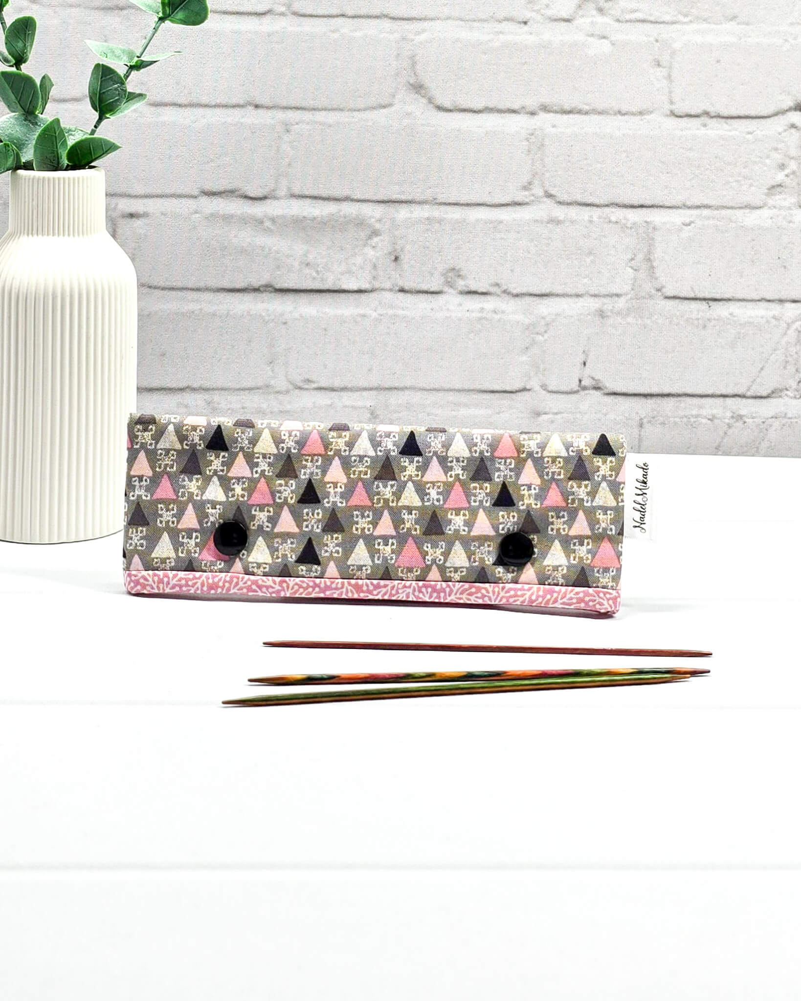Nadelgarage für 15 cm lange Nadelspiele sichert das Sockenstrickzeug und verhindert fallengelassene Maschen. Grafisches Retromuster mit kleinen Dreiecken in Rosa, Grau und Schwarz. Handgenäht in Bayern von Nadelmikado