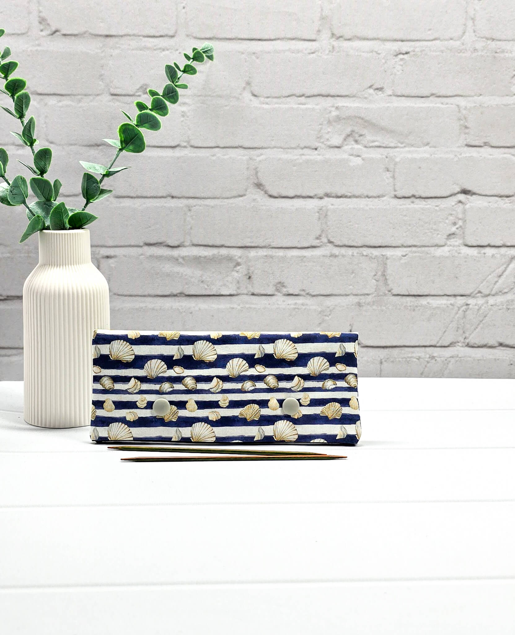 Nadelgarage für 15cm Nadelspiele aus blau-weiß gestreiftem Stoff mit Muschelmotiven und zwei hellgrauen Druckknöpfen. Handgenäht in Bayern von Nadelmikado. 
