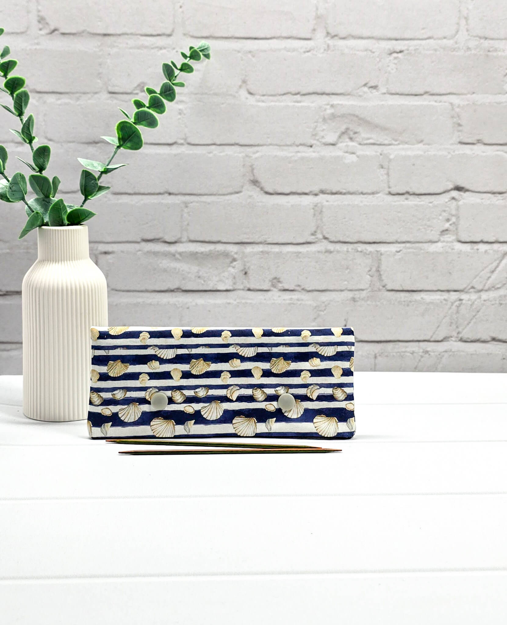 Nadelgarage für 15cm Nadelspiele aus blau-weiß gestreiftem Stoff mit Muschelmotiven und zwei hellgrauen Druckknöpfen. Handgenäht in Bayern von Nadelmikado. 