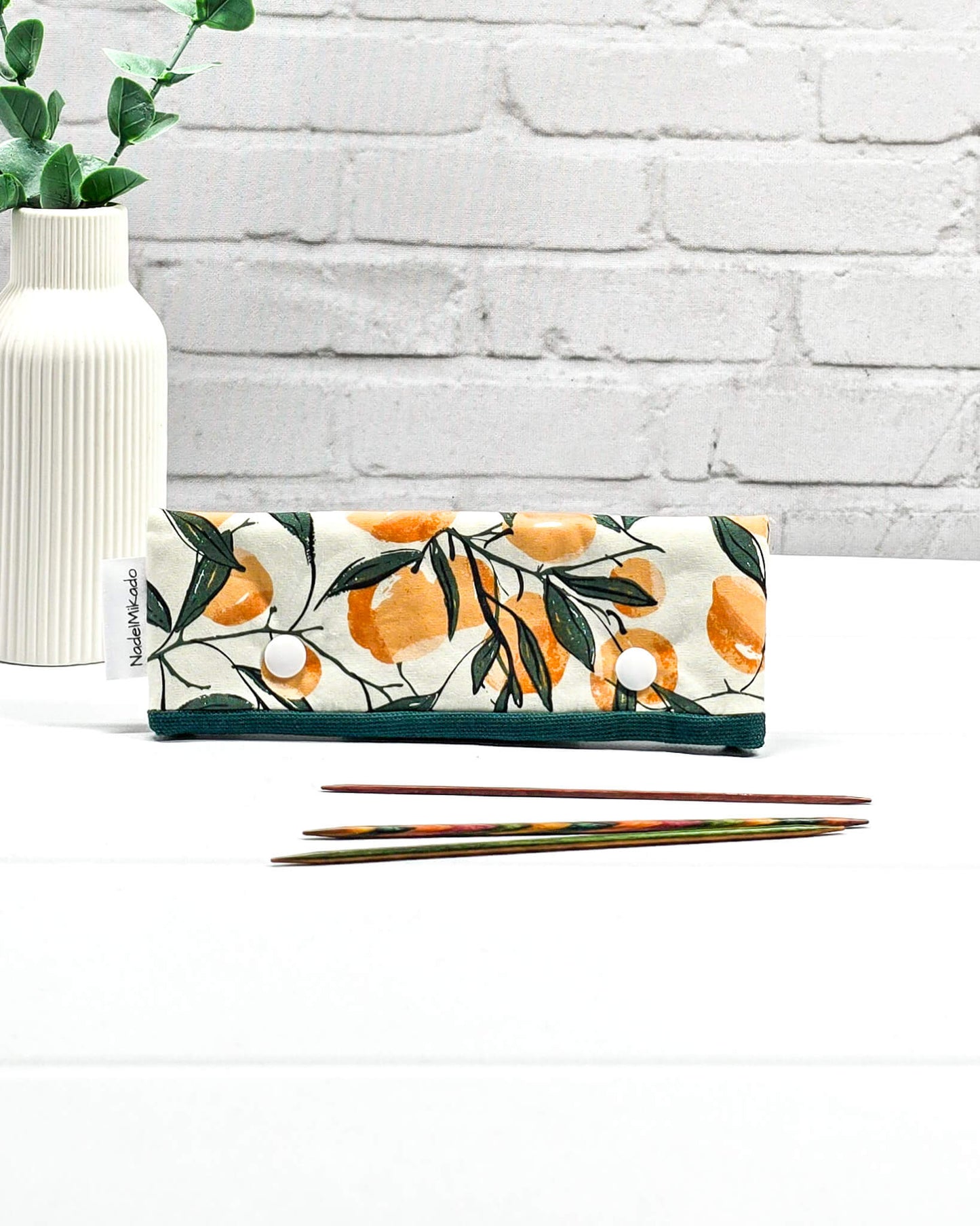 Nadelgarage für 15 cm lange Nadelspiele sichert das Sockenstrickzeug und verhindert fallengelassene Maschen. Botanisches Motiv mit Orangen an grünen Zweigen auf hellem Stoff. Handgenäht in Bayern von Nadelmikado.