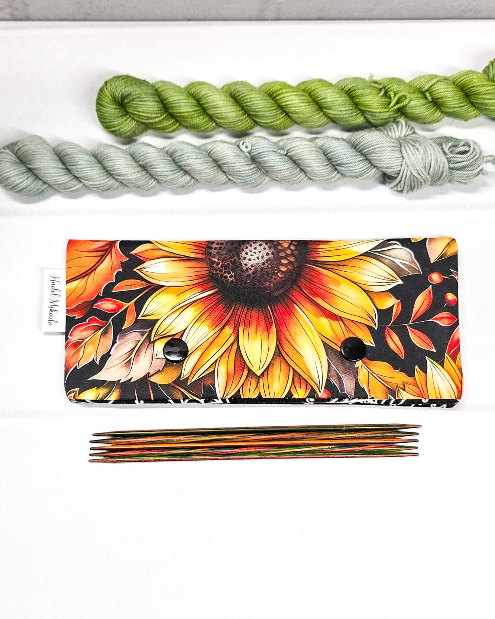 Nadelgarage für 15 cm lange Nadelspiele mit zwei schwarzen Druckknöpfen und großem Sonnenblumen-Motiv auf dunklem Grund. Handgenäht in Bayern von Nadelmikado.