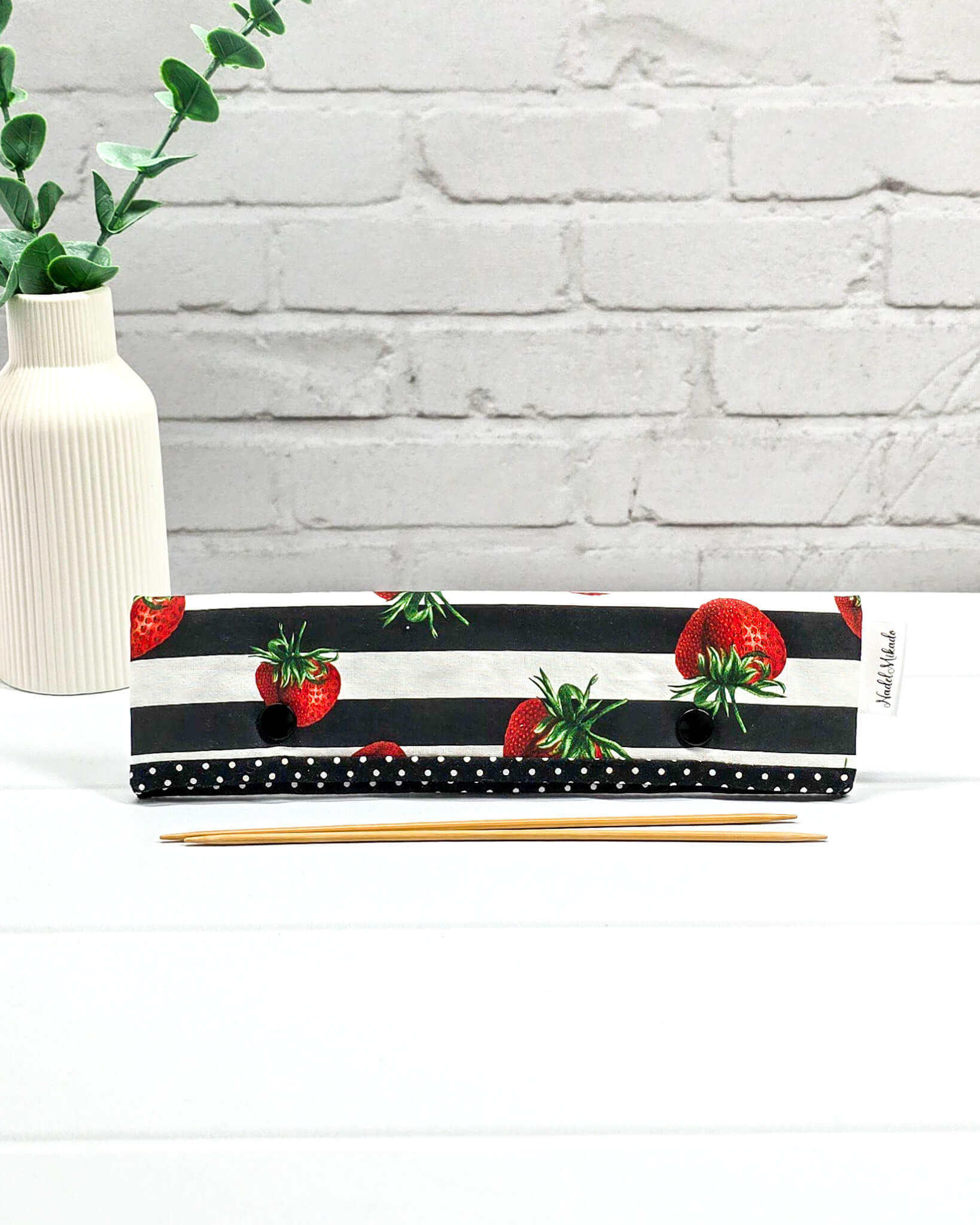 Nadelgarage für 20 cm Nadelspiele mit großen Erdbeeren auf schwarz-weiß gestreiftem Stoff und schwarzen Druckknöpfen. Handgenäht in Bayern von Nadelmikado