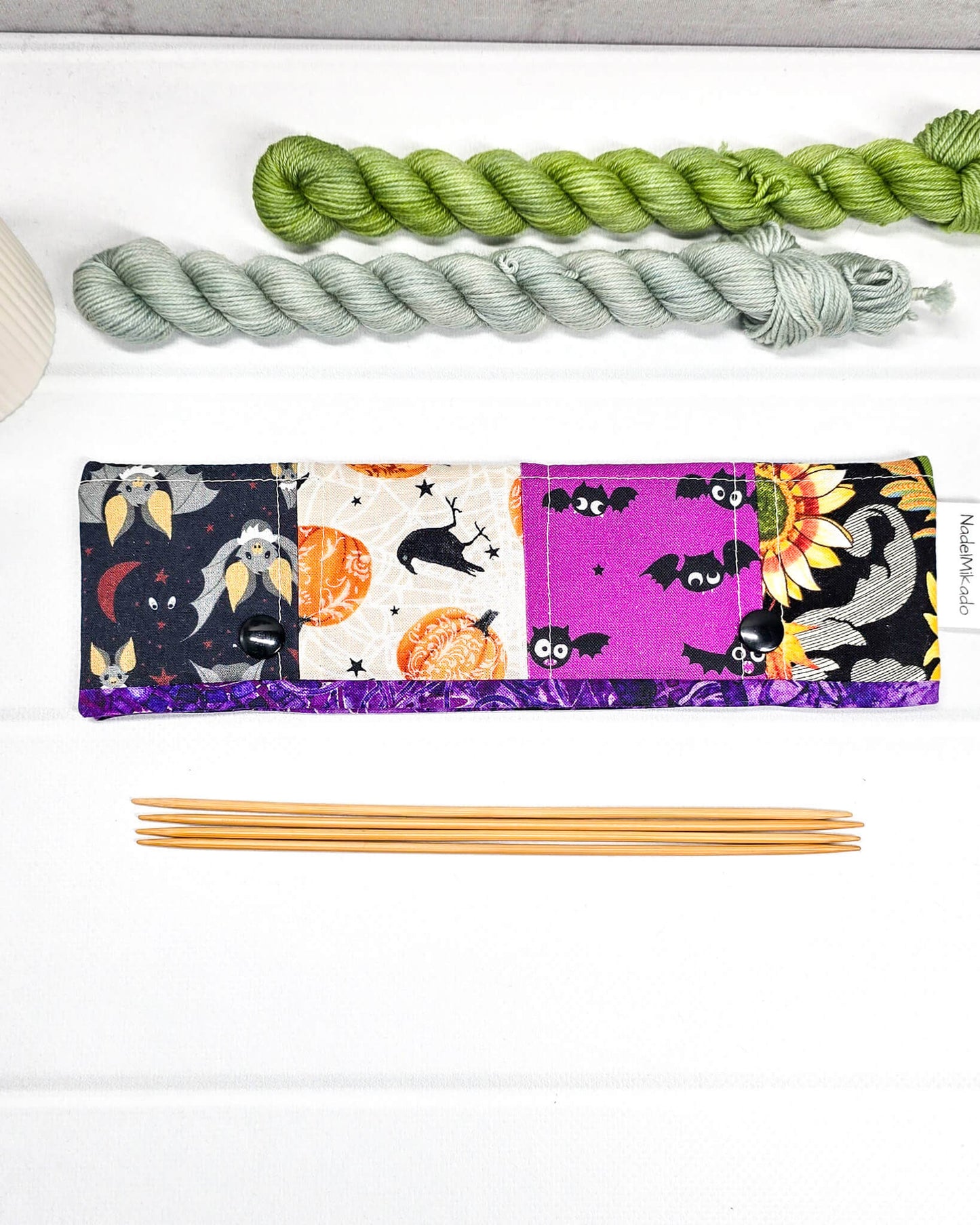 Nadelgarage für 20 cm Nadelspiele im Patchwork-Design mit Totenköpfen, Spinnennetzen auf Orange und floralen Mustern sowie schwarzen Druckknöpfen. Handgenäht in Bayern von Nadelmikado.