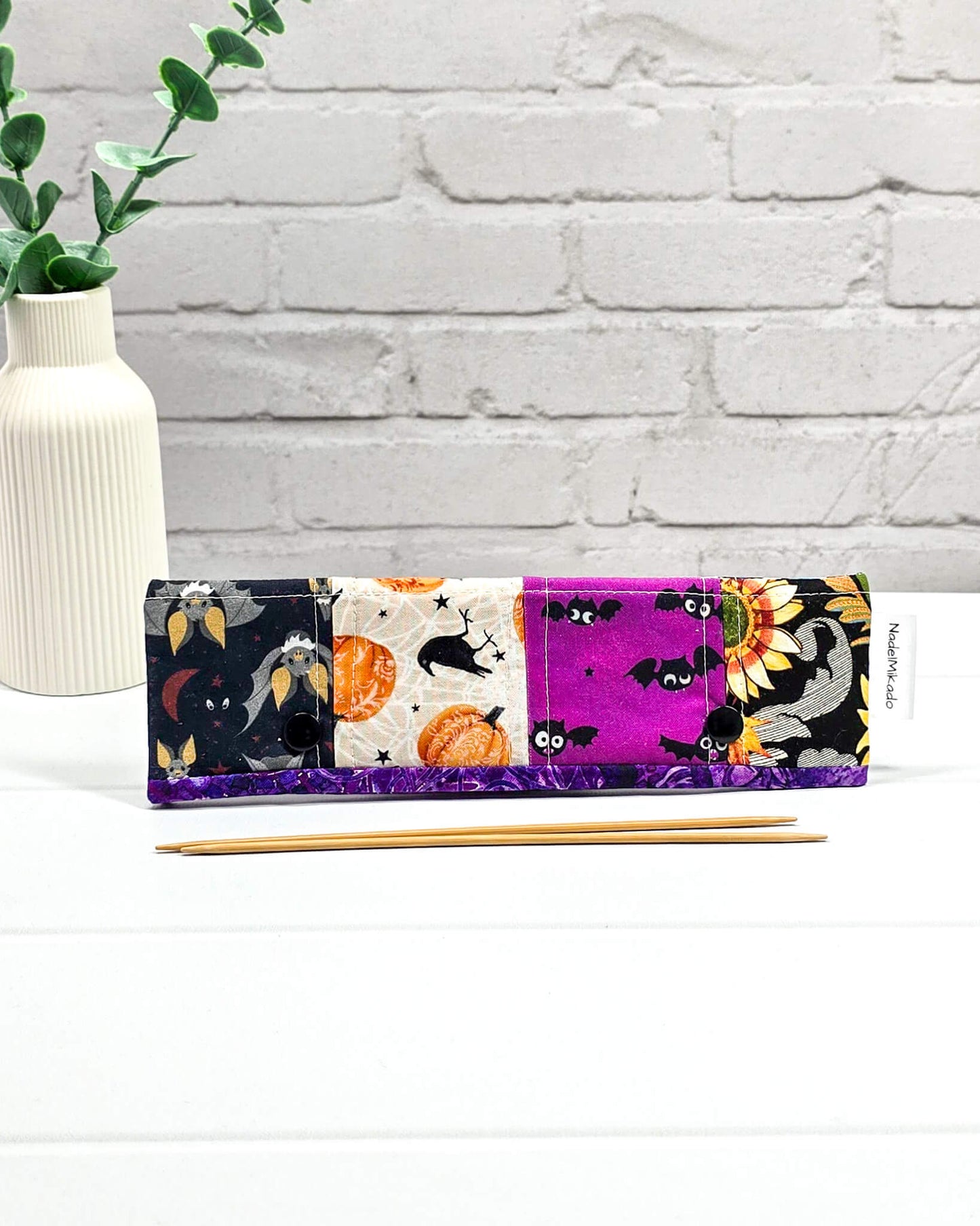 Nadelgarage für 20 cm Nadelspiele im Patchwork-Design mit Totenköpfen, Spinnennetzen auf Orange und floralen Mustern sowie schwarzen Druckknöpfen. Handgenäht in Bayern von Nadelmikado.