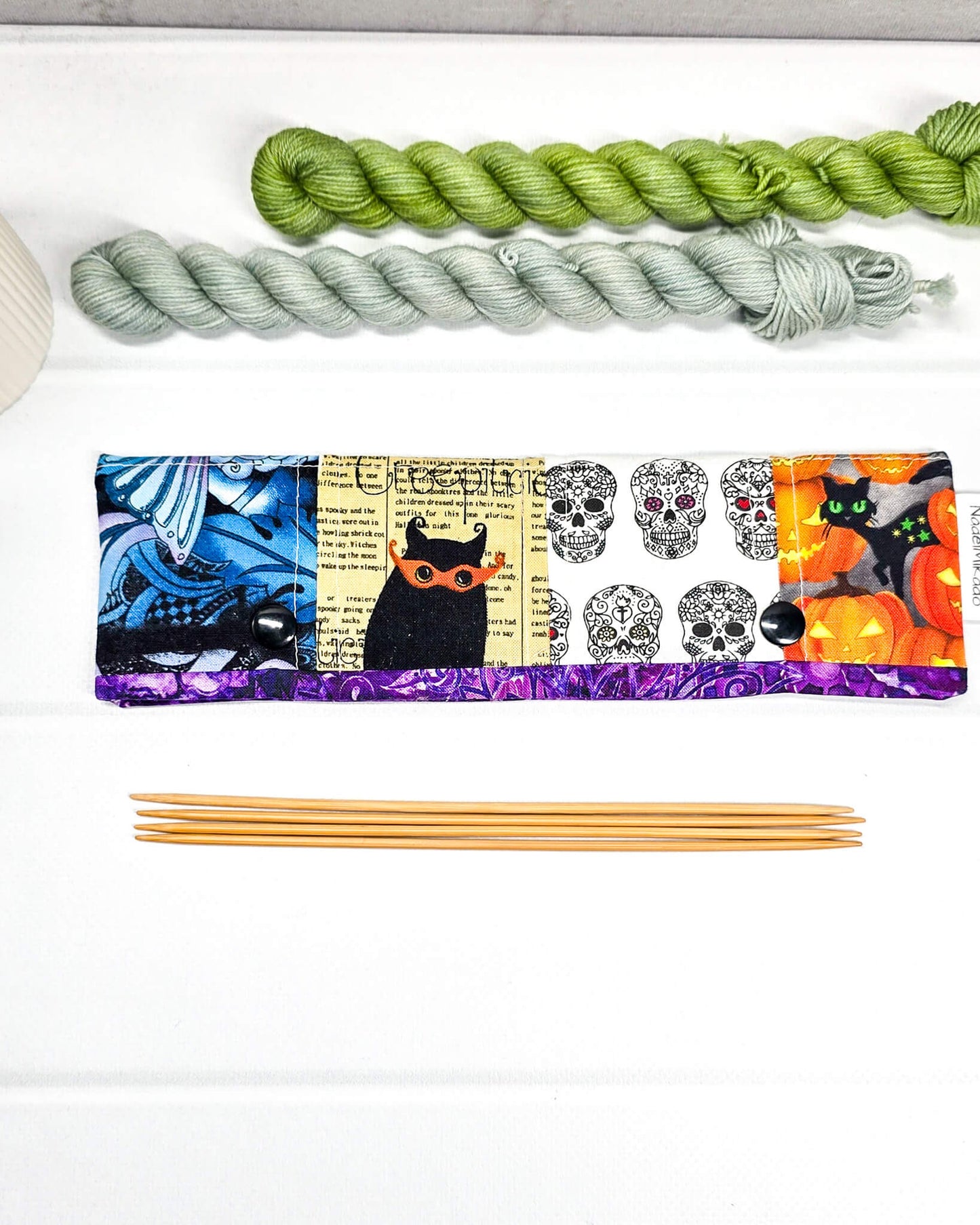 Nadelgarage für 20 cm Nadelspiele im Patchwork-Stil mit Motiven von Totenköpfen, Kürbissen und abstrakten violetten Mustern sowie schwarzen Druckknöpfen. Handgenäht in Bayern von Nadelmikado
