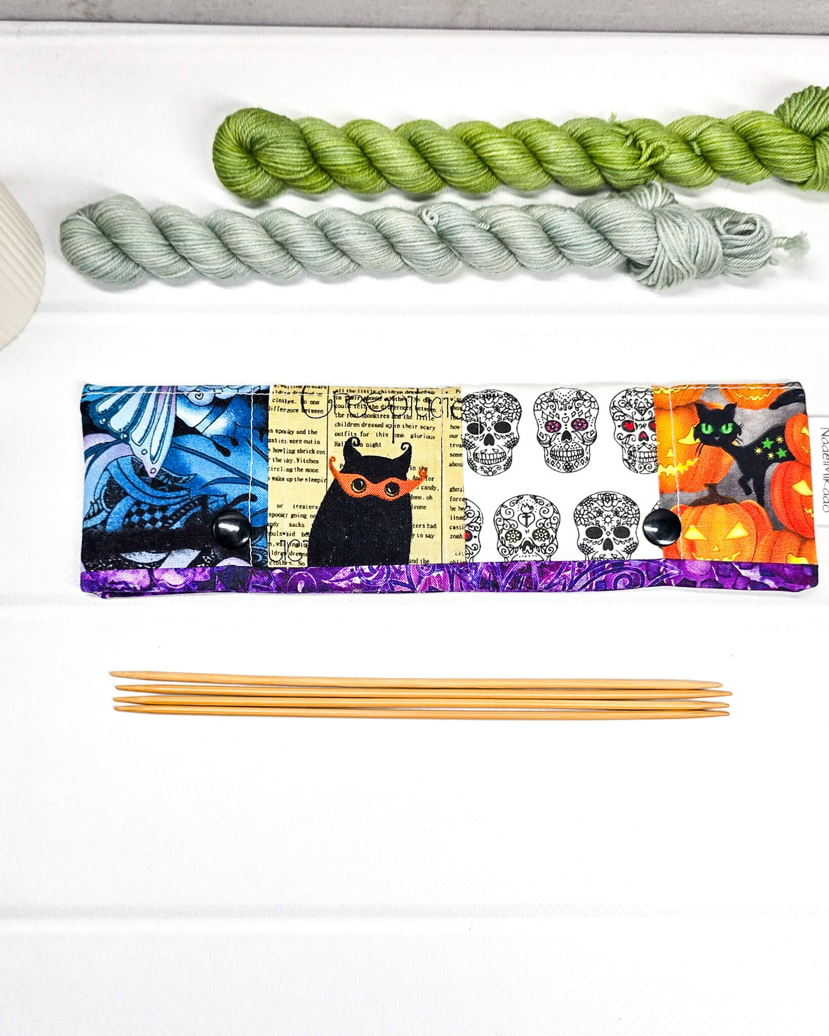 Nadelgarage für 20 cm Nadelspiele im Patchwork-Stil mit Motiven von Totenköpfen, Kürbissen und abstrakten violetten Mustern sowie schwarzen Druckknöpfen. Handgenäht in Bayern von Nadelmikado