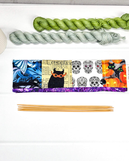 Nadelgarage für 20 cm Nadelspiele im Patchwork-Stil mit Motiven von Totenköpfen, Kürbissen und abstrakten violetten Mustern sowie schwarzen Druckknöpfen. Handgenäht in Bayern von Nadelmikado
