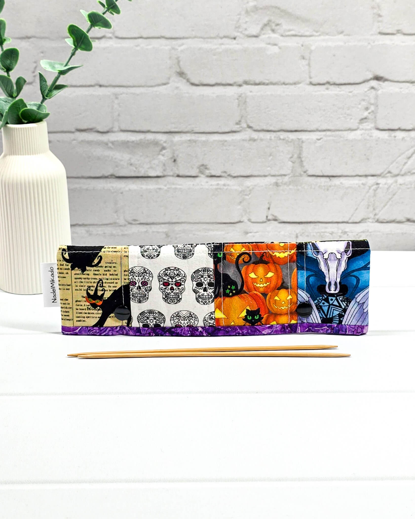 Nadelgarage für 20 cm Nadelspiele im Patchwork-Stil mit Halloween-Motiven wie schwarzen Katzen, Totenköpfen, Kürbissen und einem Vampirgnom-Design. Handgenäht in Bayern von Nadelmikado.