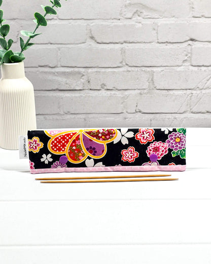 Nadelgarage für 20 cm Nadelspiele mit großen bunten Blumenmotiven im japanischen Stil auf schwarzem Stoff und lila Druckknöpfen. Handgenäht in Bayern von Nadelmikado.
